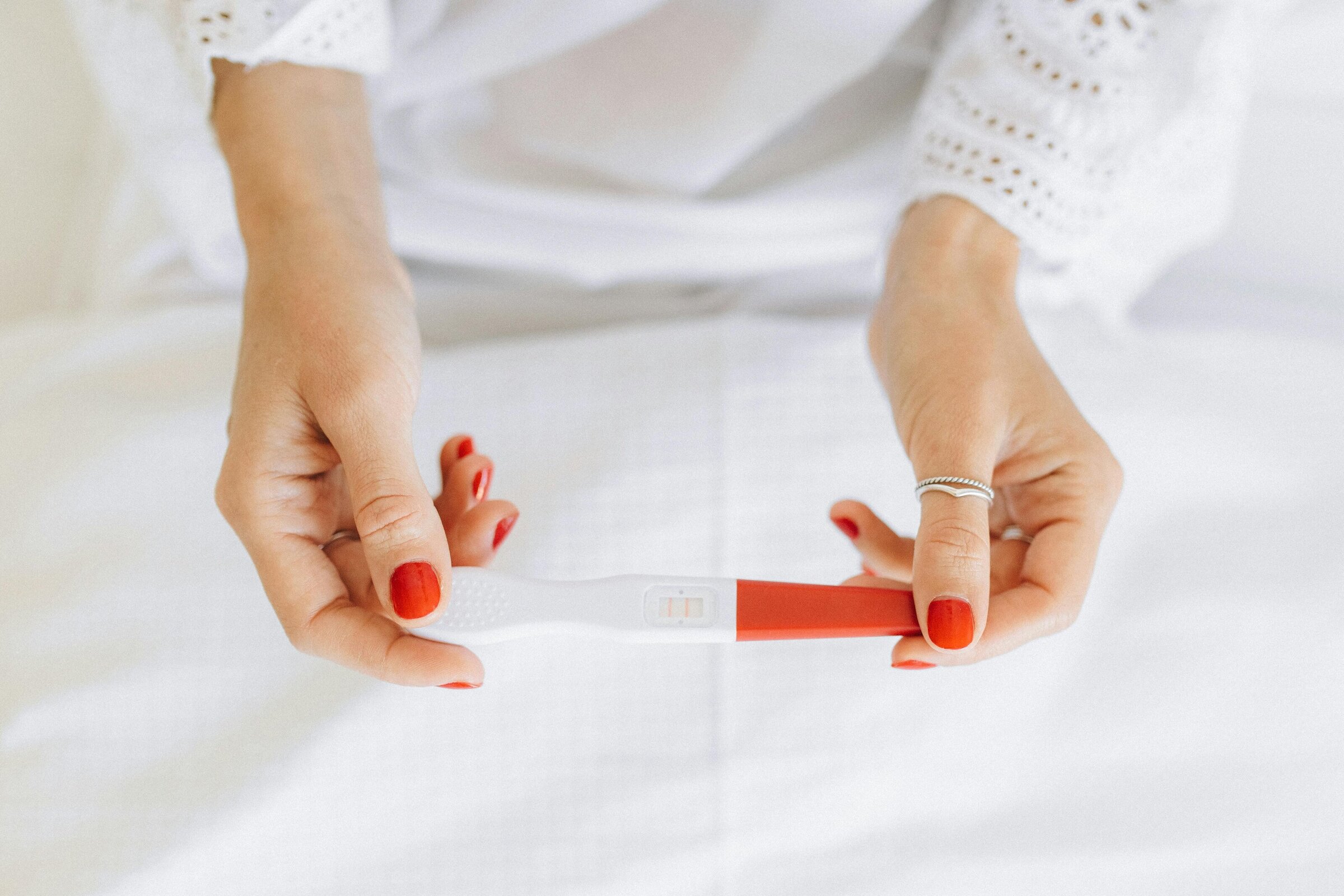 Hands holding a positive pregnancy test while trying to conceive.
